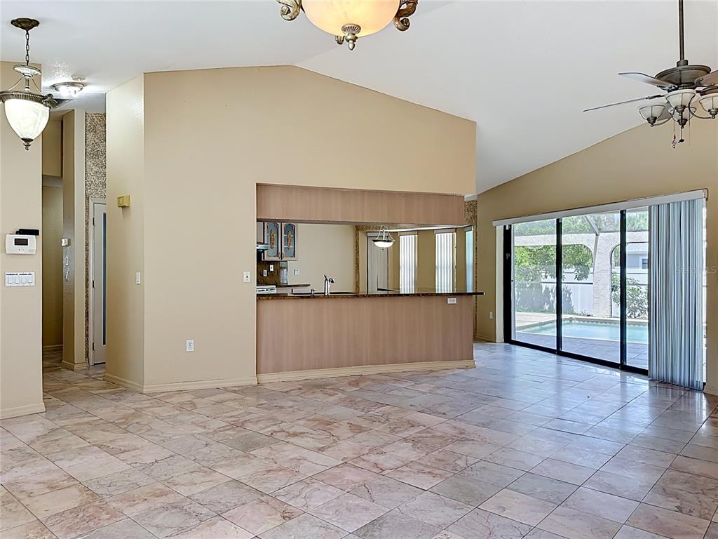 A living area with tile flooring, a kitchen pass-through, and sliding doors to a pool — 4354 BOGGS STREET, PORT CHARLOTTE, FL