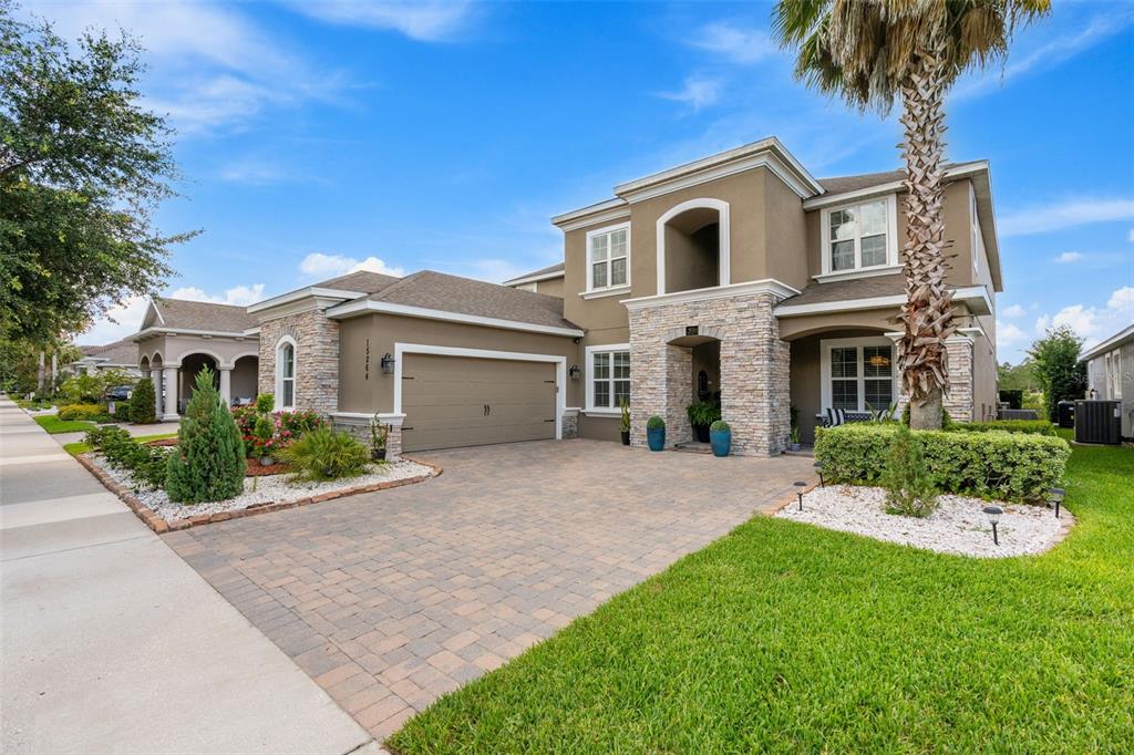 A two-story house with a stone facade, a paved driveway, and a palm tree — 15264 SHONAN GOLD DRIVE, WINTER GARDEN, FL