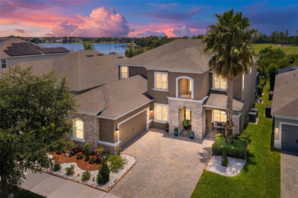 An aerial view of a two-story suburban house with a stone facade and paver driveway — 15264 SHONAN GOLD DRIVE, WINTER GARDEN, FL