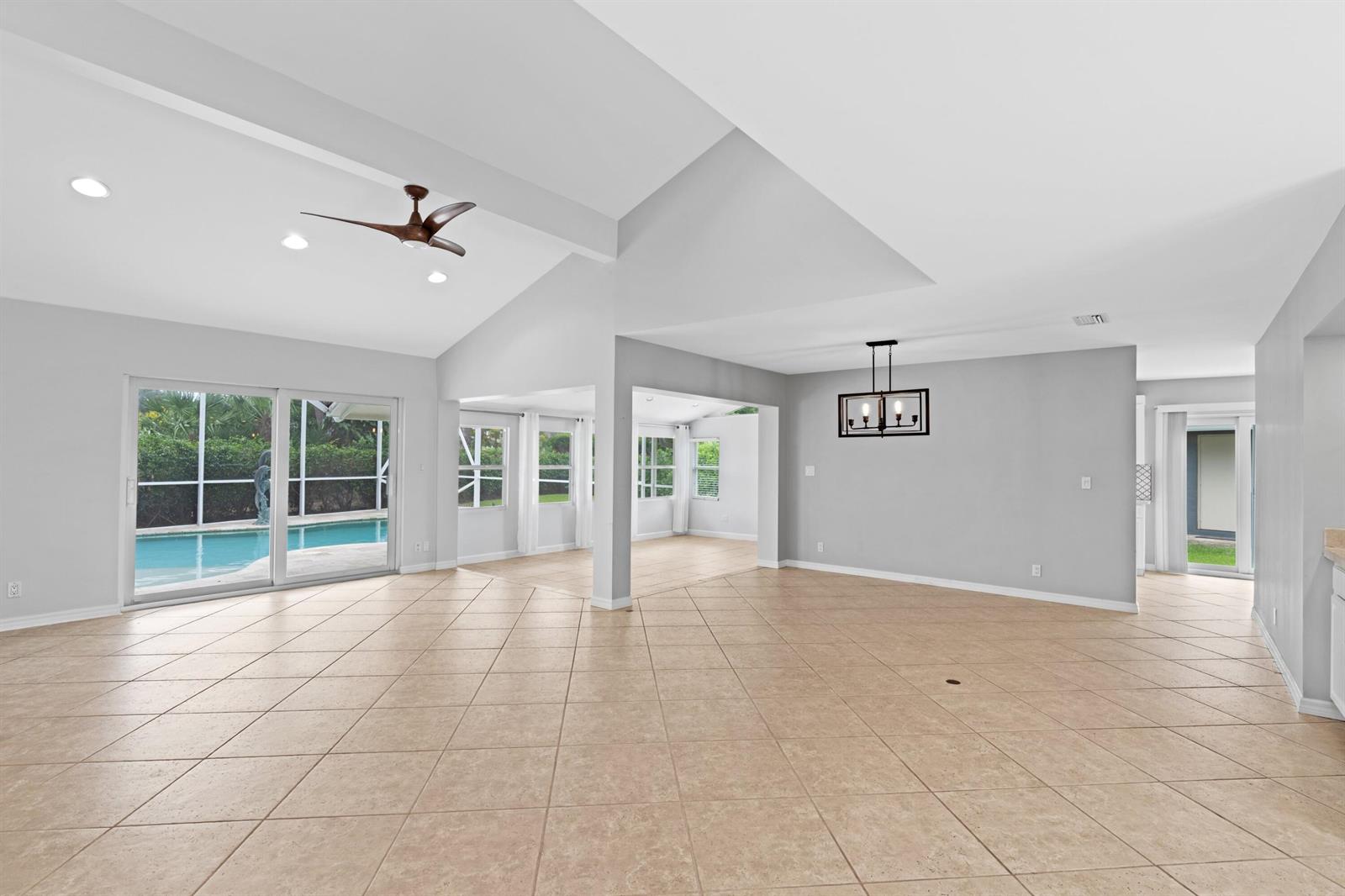 An open-concept living area with vaulted ceilings, tile flooring, and a view of a pool — 925 Foxpointe Circle, Delray Beach FL 33445, DELRAY BEACH, FL