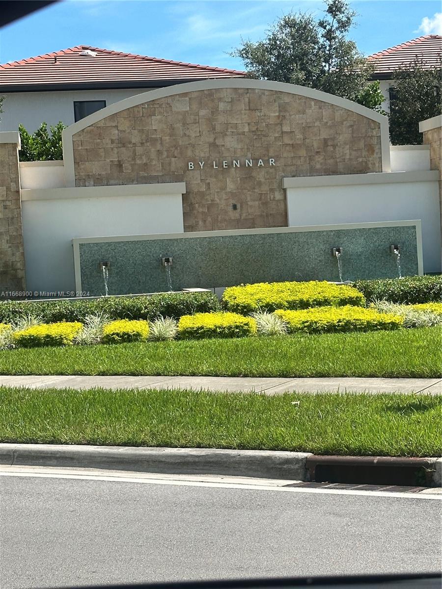 A stone-faced community entrance sign features a water fountain and manicured landscaping — 3415 W 112th Ter, Hialeah FL 33018, HIALEAH, FL