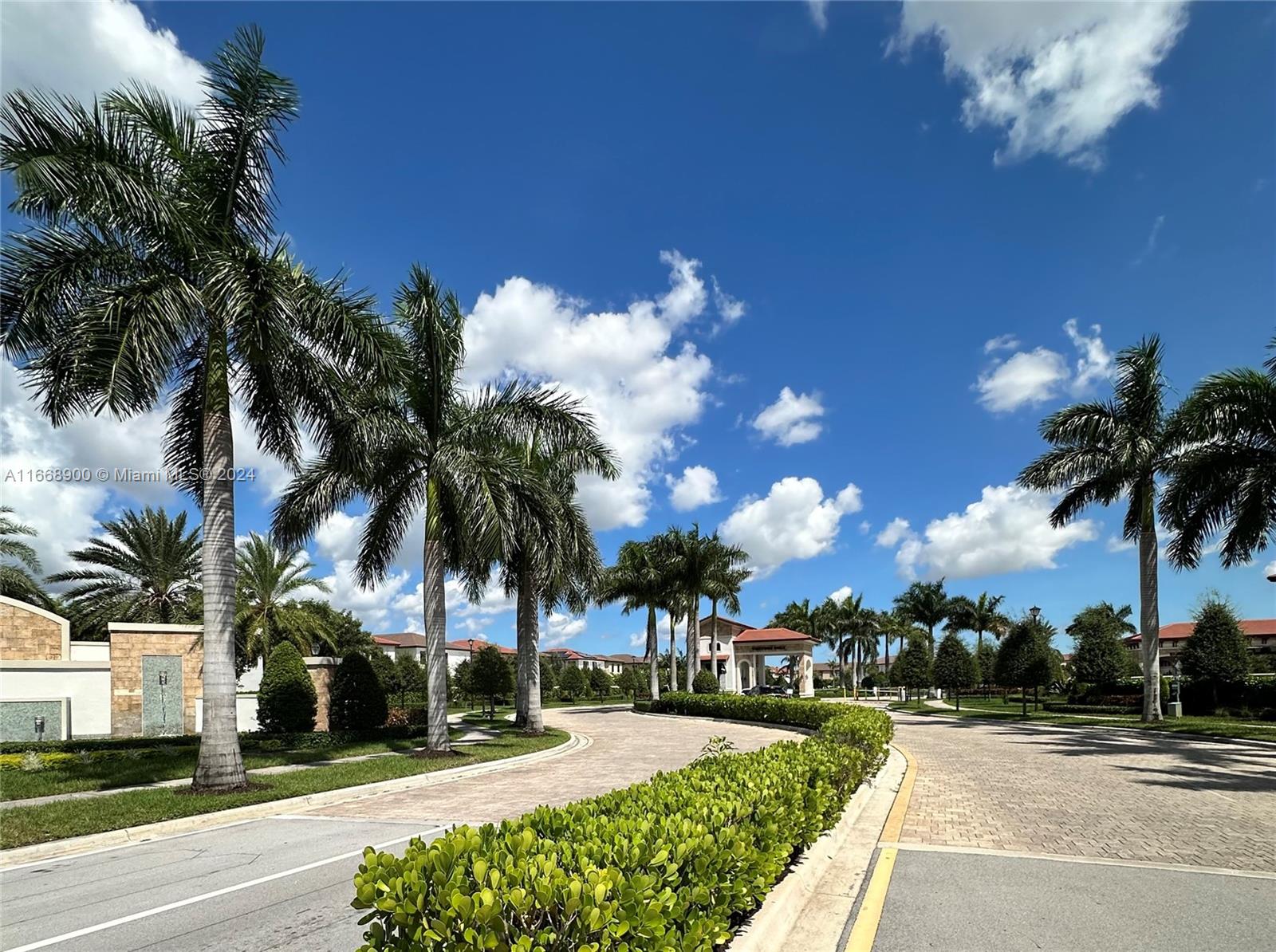 A paved driveway leads toward a gated entrance lined with palm trees and manicured hedges — 3415 W 112th Ter, Hialeah FL 33018, HIALEAH, FL