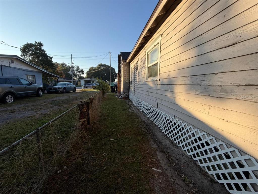 A side view of a house with light-colored siding, lattice skirting, and a chain-link fence — 4427 RALEIGHT STREET, ORLANDO, FL