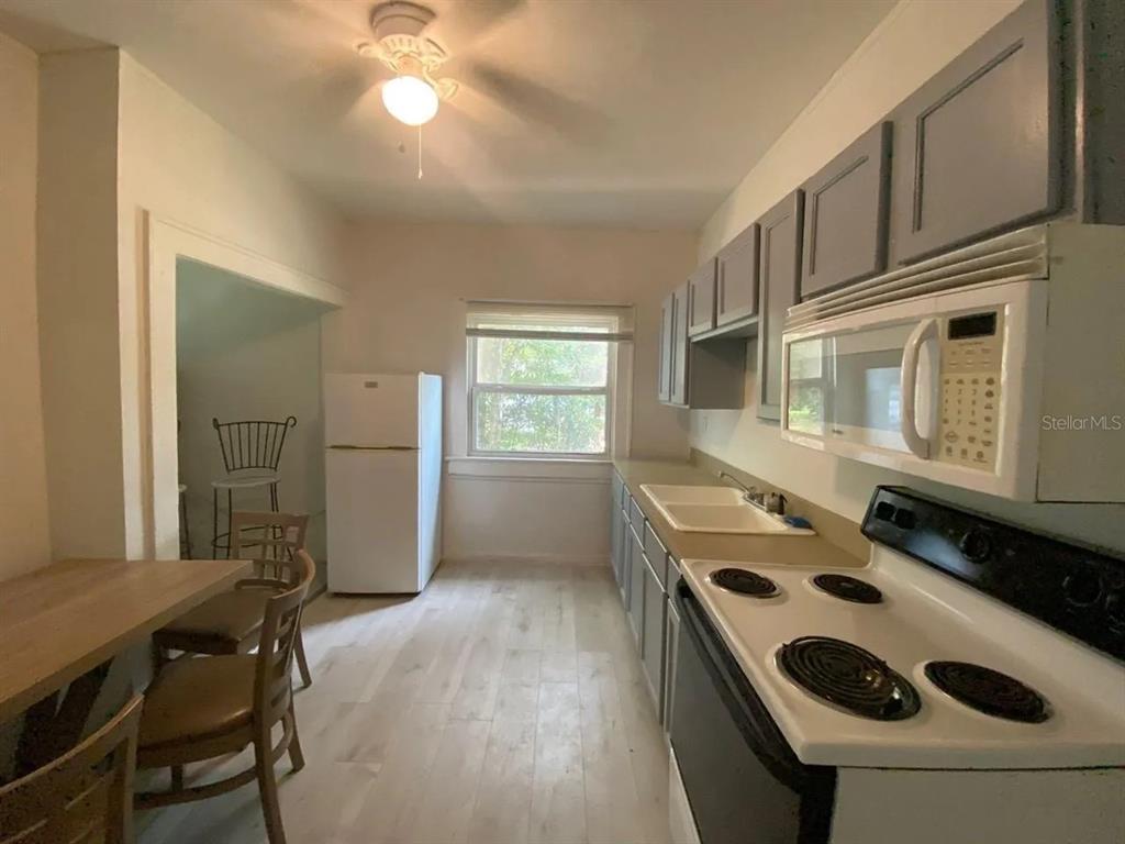 A kitchen features gray cabinets, white appliances, a light wood table, and light-colored flooring — 4427 RALEIGHT STREET, ORLANDO, FL