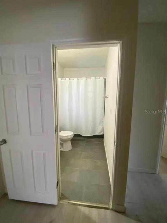 A view through an open doorway into a bathroom with gray tile flooring and shower — 4427 RALEIGHT STREET, ORLANDO, FL