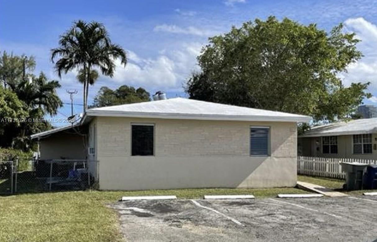 The exterior of a single-story residential building features light-colored siding, a flat roof, and parking — 409 SW 4th Ter, Hallandale Beach FL 33009, HALLANDALE BEACH, FL
