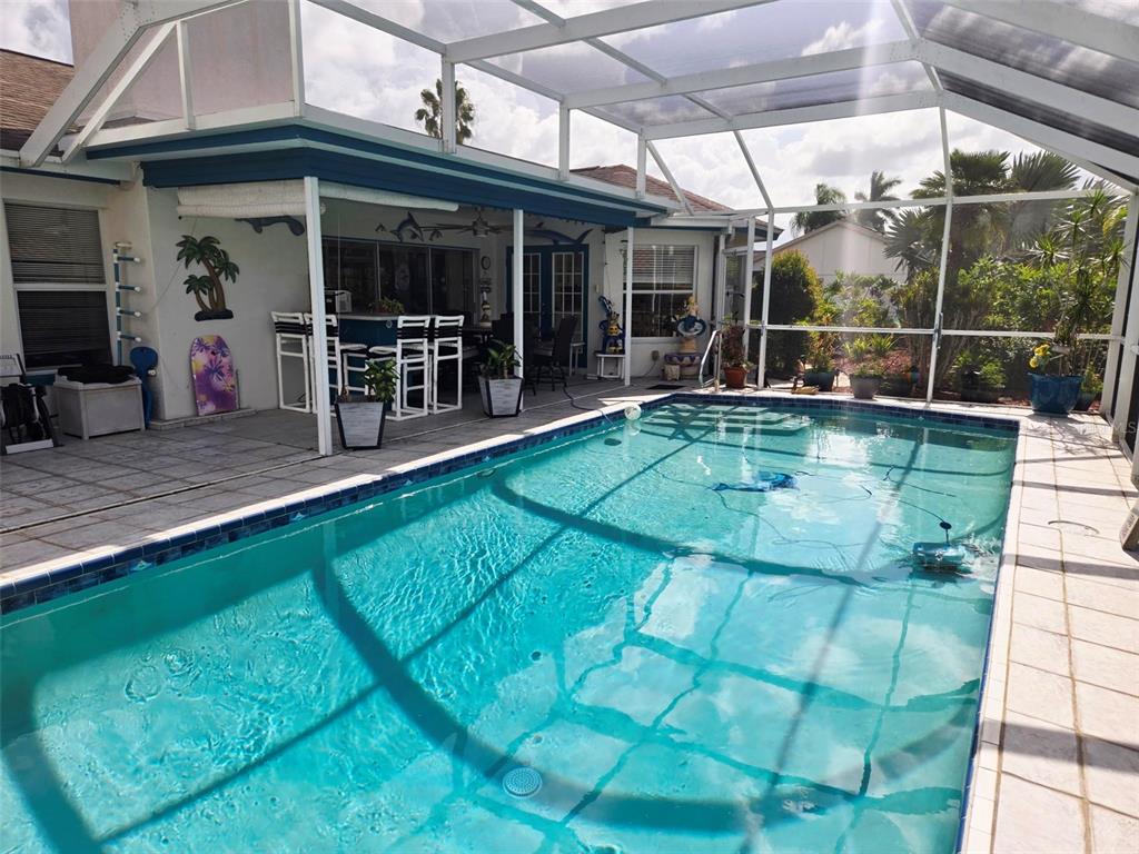 A swimming pool with a screen enclosure sits on a patio next to a house — 4236 PRO AM AVE E, BRADENTON, FL