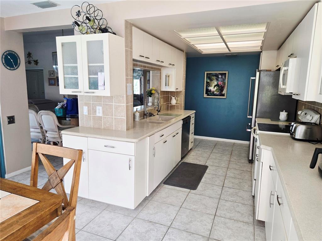 A kitchen features white cabinets, light countertops, tile flooring, and a blue accent wall — 4236 PRO AM AVE E, BRADENTON, FL