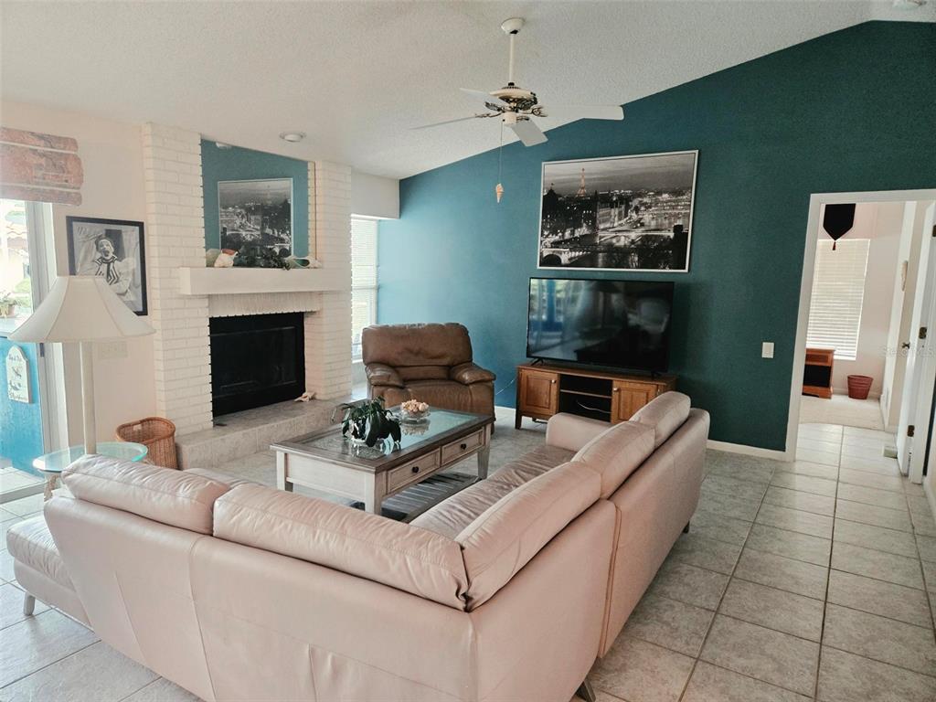 A living room features a white brick fireplace, a teal accent wall, and tile flooring — 4236 PRO AM AVE E, BRADENTON, FL