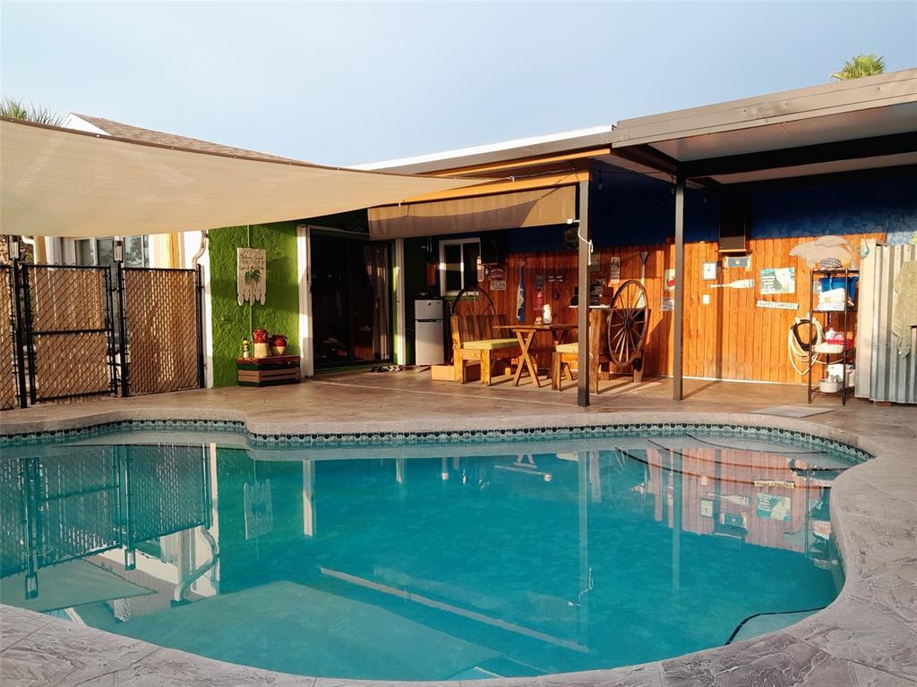 A swimming pool sits in front of a covered patio with wooden walls and furniture — 6417 KLAUS COURT, PORT CHARLOTTE, FL