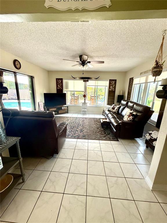 A living room features tile flooring, a ceiling fan, a television, and leather furniture — 6417 KLAUS COURT, PORT CHARLOTTE, FL
