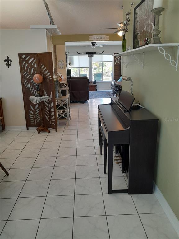 A digital piano sits on a tiled floor in a room leading to a living area — 6417 KLAUS COURT, PORT CHARLOTTE, FL