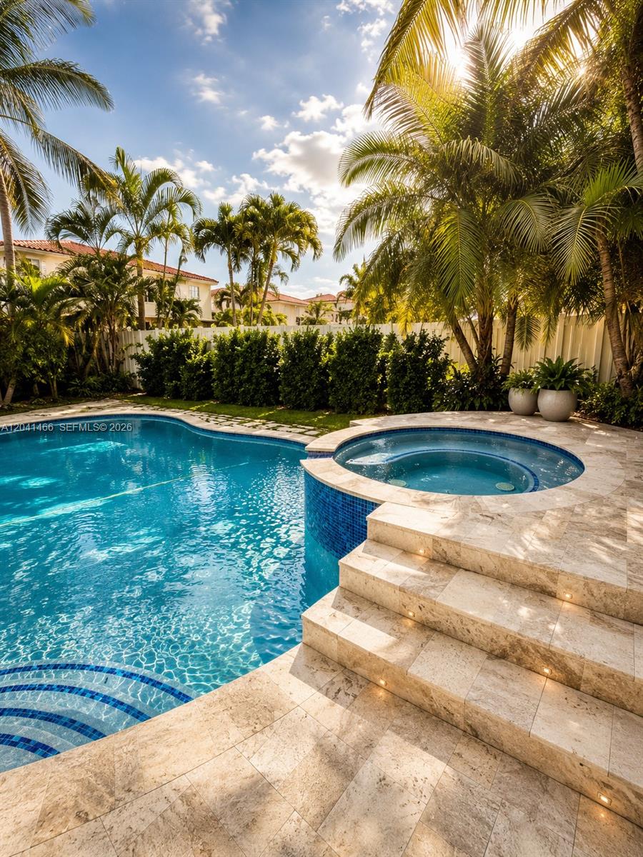A swimming pool with an attached raised spa and stone patio surrounded by palm trees — 85 Gables Blvd, Weston FL 33326, WESTON, FL