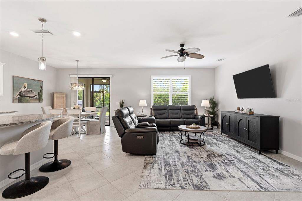 A living room with tile floors, a black leather sofa, and an adjacent dining area — 2501 SHERMAN OAK DRIVE, NORTH PORT, FL