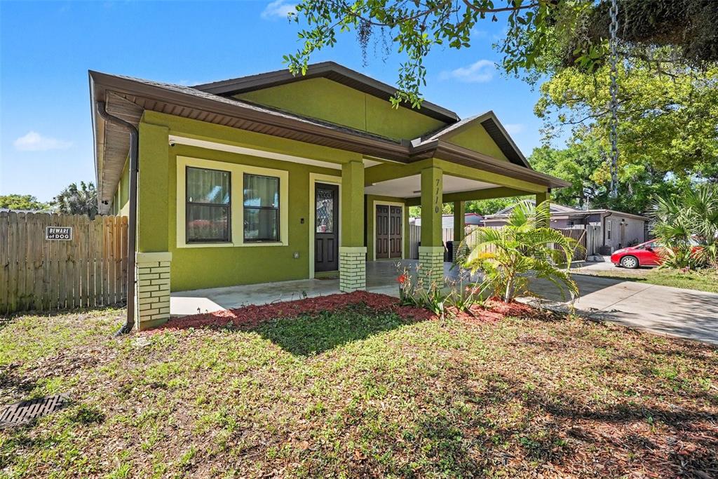 A green single-story house with a covered porch and a concrete driveway — 7110 N TALIAFERRO AVENUE, TAMPA, FL