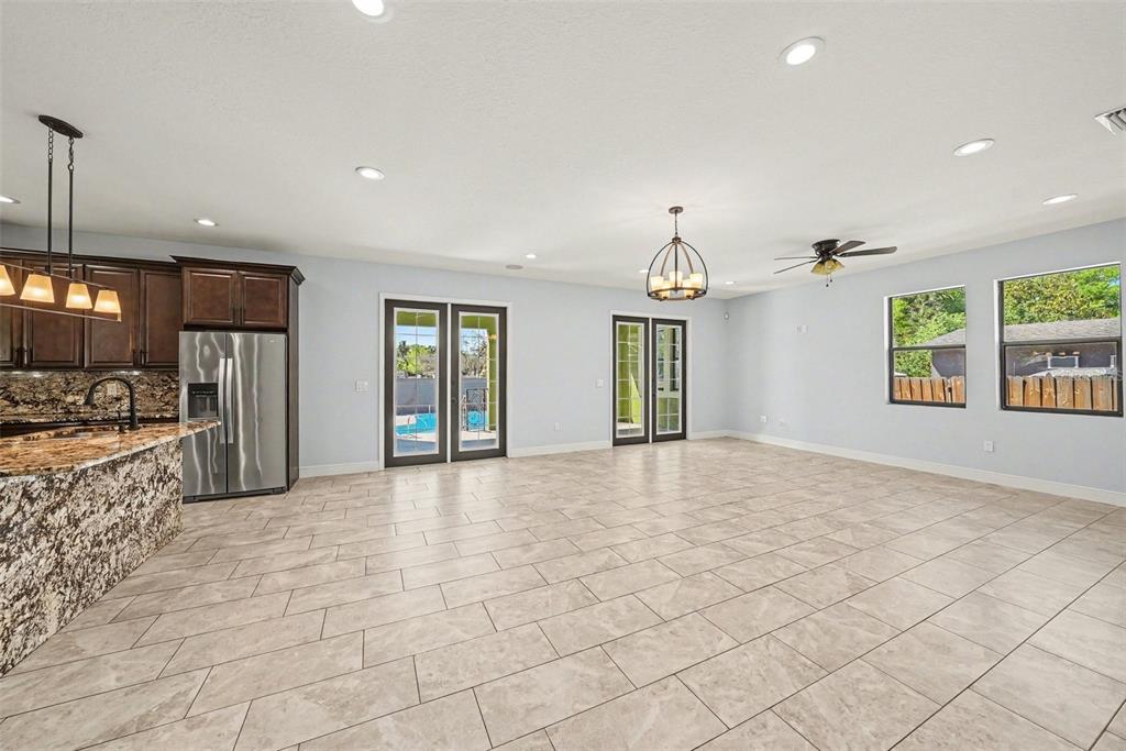 A spacious kitchen and living area with tile floors, dark wood cabinets, and two glass doors — 7110 N TALIAFERRO AVENUE, TAMPA, FL
