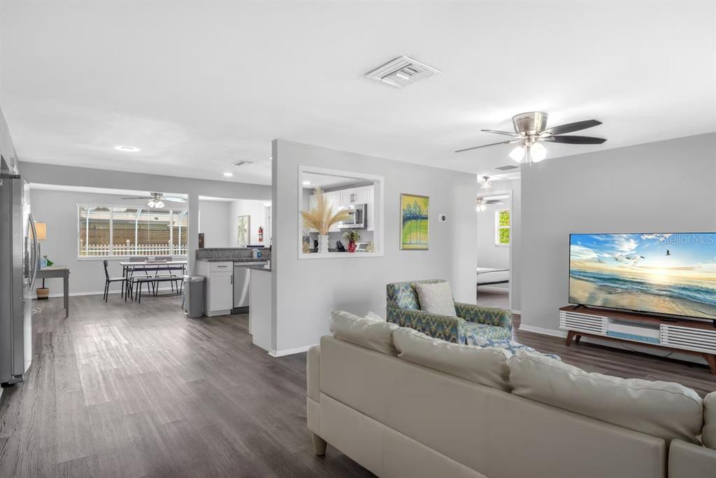 A living room with gray flooring, a white sofa, and a view into the kitchen — 8628 MAGNOLIA DRIVE, SEMINOLE, FL