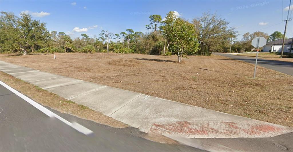 A vacant, grassy corner lot features a sidewalk and a stop sign — 16582 CAPE HORN BOULEVARD, PUNTA GORDA, FL