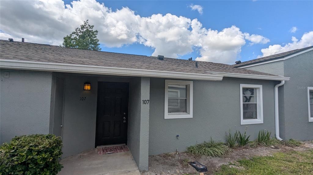 A gray exterior of a single-story home with a black front door and white trim — 107 DORCHESTER SQUARE, LAKE MARY, FL