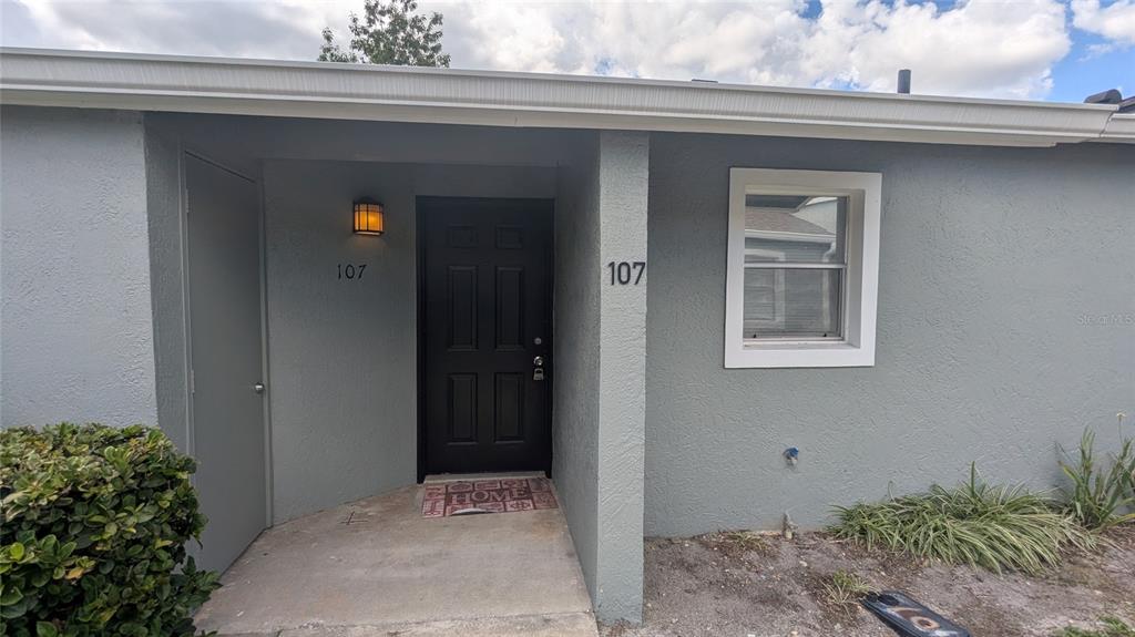 The exterior of a gray house features a black front door and a single window — 107 DORCHESTER SQUARE, LAKE MARY, FL