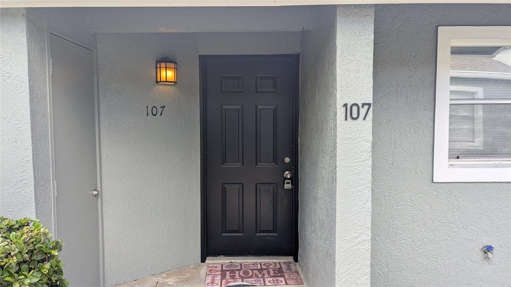 A black front door with the number 107 is centered between a side door and window — 107 DORCHESTER SQUARE, LAKE MARY, FL