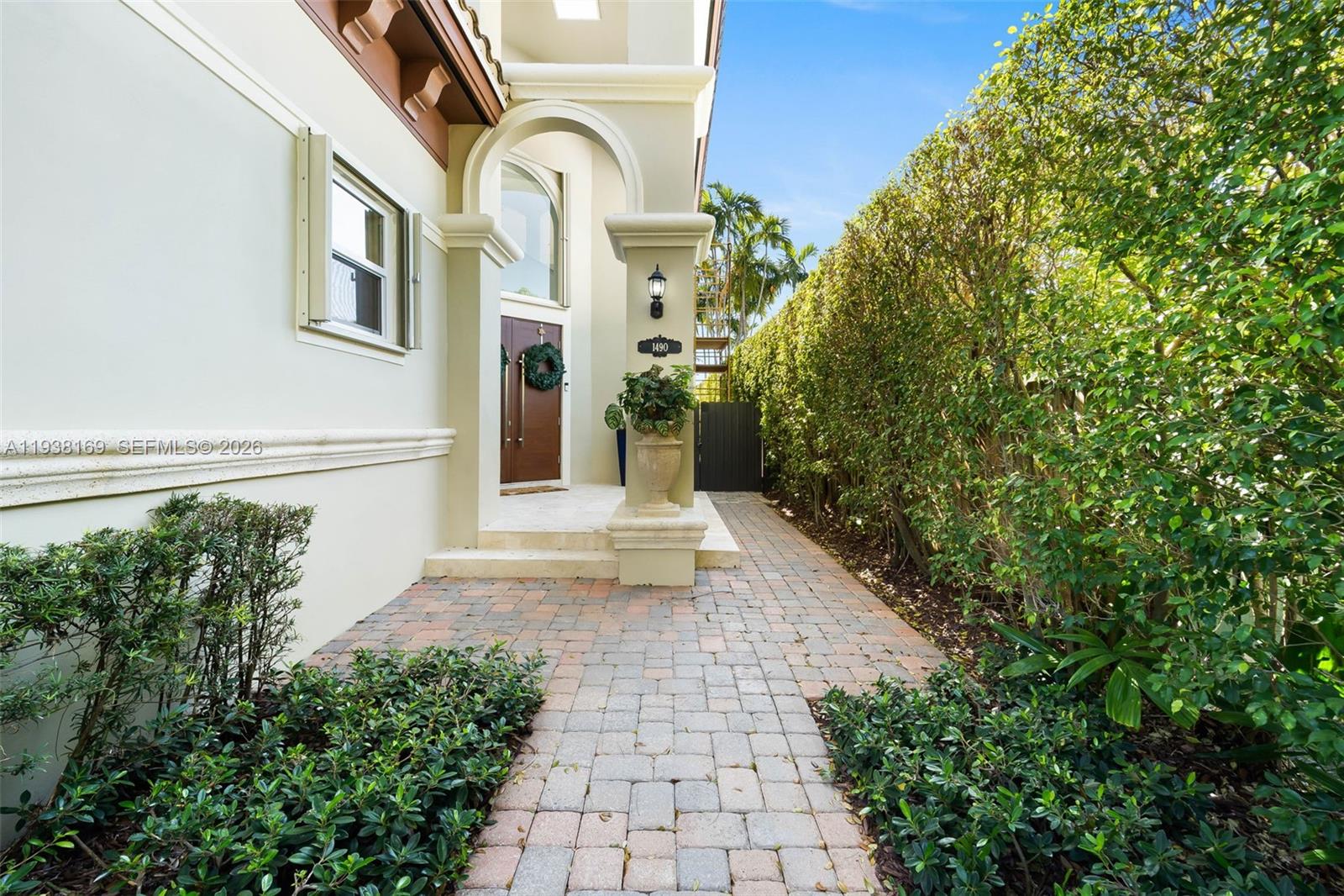 A paved walkway leads to the front entrance of a house with a tall hedge — 1490 Cleveland Rd, Miami Beach FL 33141, MIAMI BEACH, FL