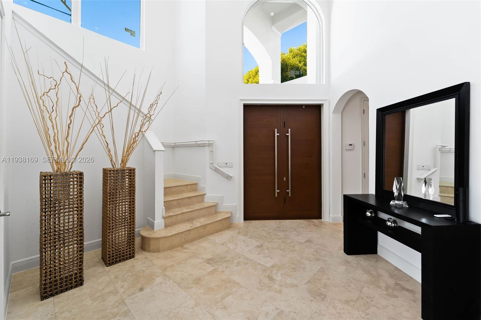 A bright entryway features a double wood door, stone tile flooring, and a staircase — 1490 Cleveland Rd, Miami Beach FL 33141, MIAMI BEACH, FL