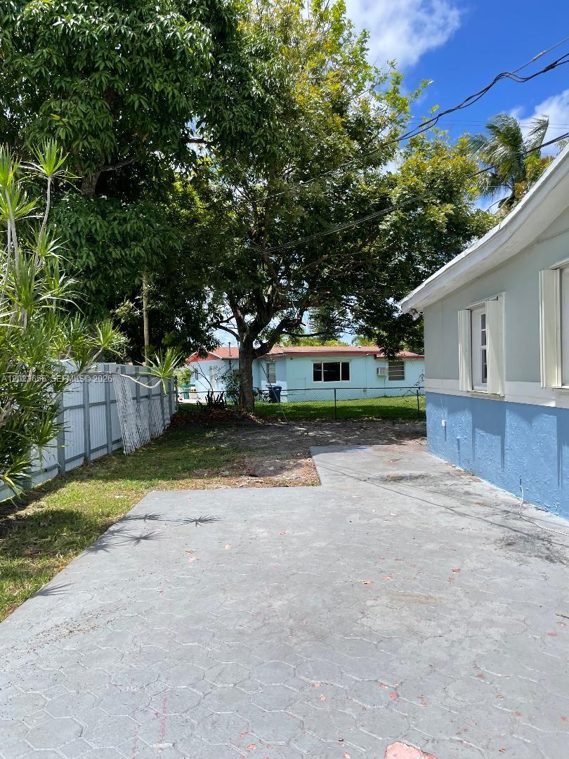 A side view of a single-story house with a red paved driveway and blue trim — 1225 NW 189th Ter, Miami Gardens FL 33169, MIAMI GARDENS, FL