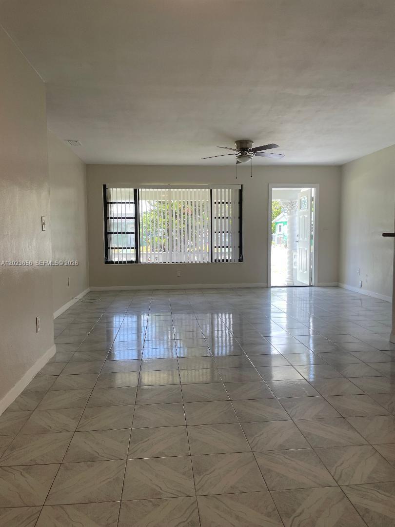 A bright living room features light-colored tile flooring, a ceiling fan, and a large window — 1225 NW 189th Ter, Miami Gardens FL 33169, MIAMI GARDENS, FL
