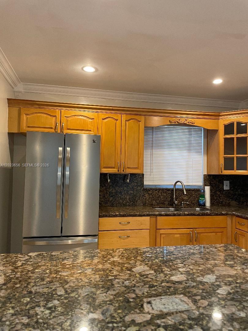 A kitchen features wood cabinets, granite countertops, and a stainless steel refrigerator — 1225 NW 189th Ter, Miami Gardens FL 33169, MIAMI GARDENS, FL