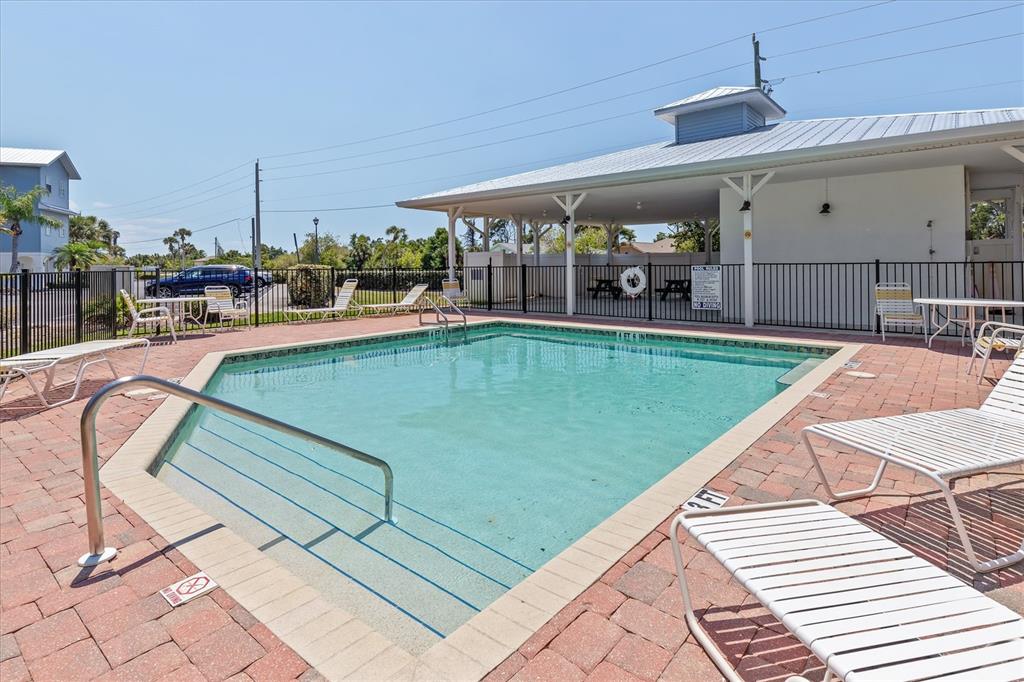 An outdoor swimming pool with lounge chairs on a brick patio under a clear sky — 3923 CAPE HAZE DRIVE UNIT 302, ROTONDA WEST, FL