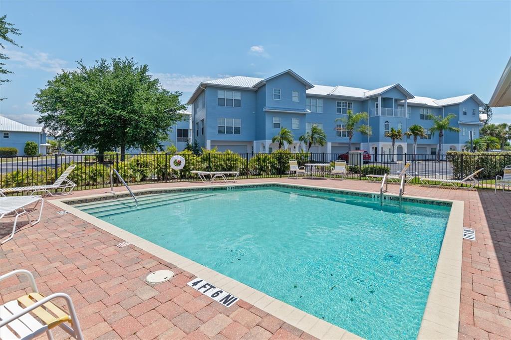 A rectangular swimming pool sits in front of a multi-story blue apartment building — 3923 CAPE HAZE DRIVE UNIT 302, ROTONDA WEST, FL