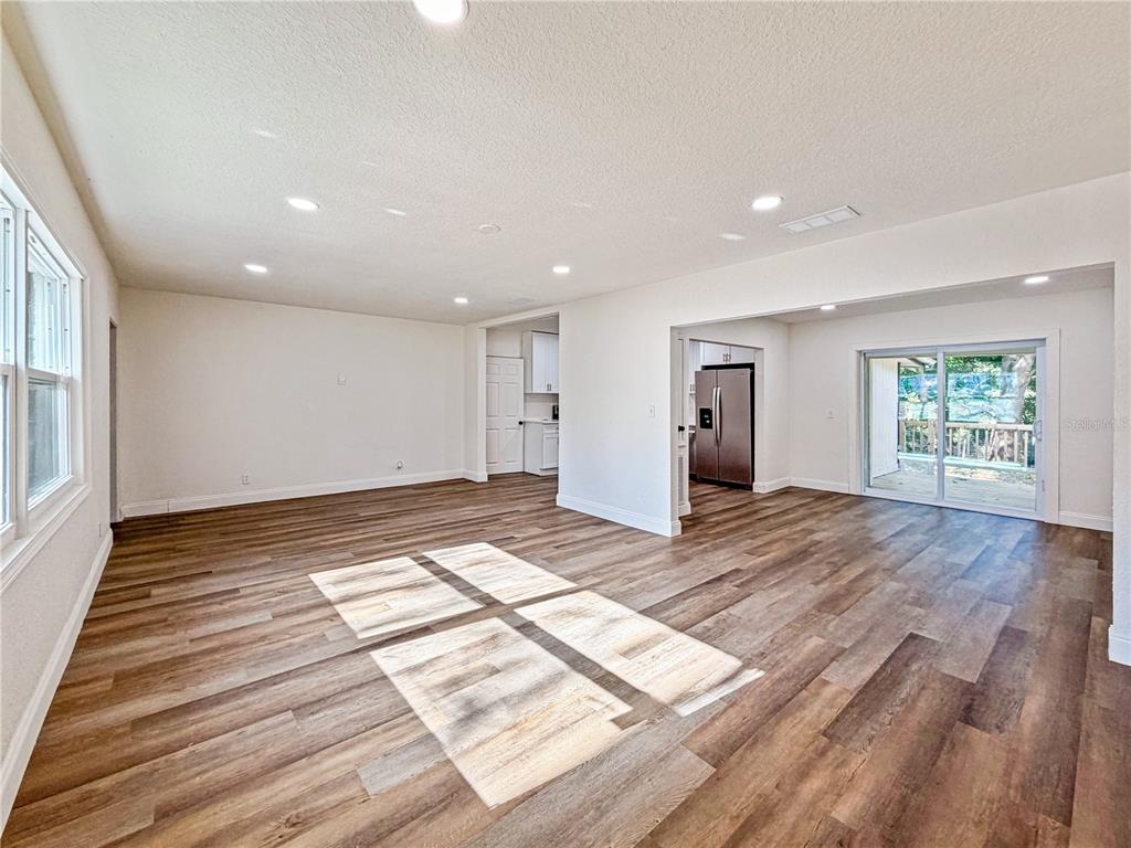 An open-concept living area features wood-look flooring, recessed lighting, and a sliding glass door — 14418 S GRAND HIGHWAY, CLERMONT, FL