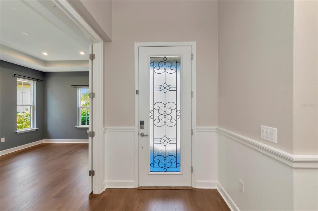 A white front door with decorative glass panels opens into a room with hardwood floors — 10187 MILKY WAY CIRCLE, SARASOTA, FL