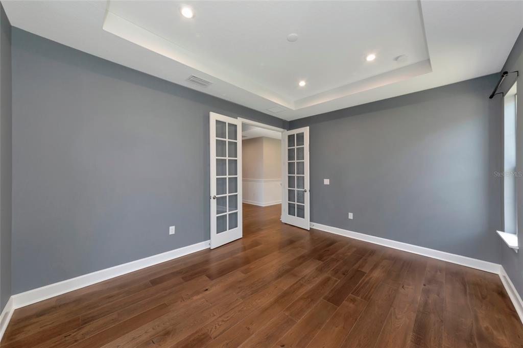A room with gray walls, hardwood floors, and French doors leading to another space — 10187 MILKY WAY CIRCLE, SARASOTA, FL