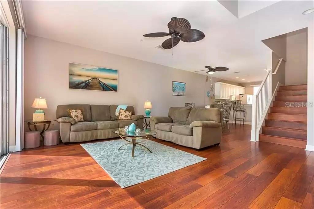 A living room with hardwood floors, two sofas, a rug, and a staircase — 8920 DUVAL LANE UNIT B15, SARASOTA, FL