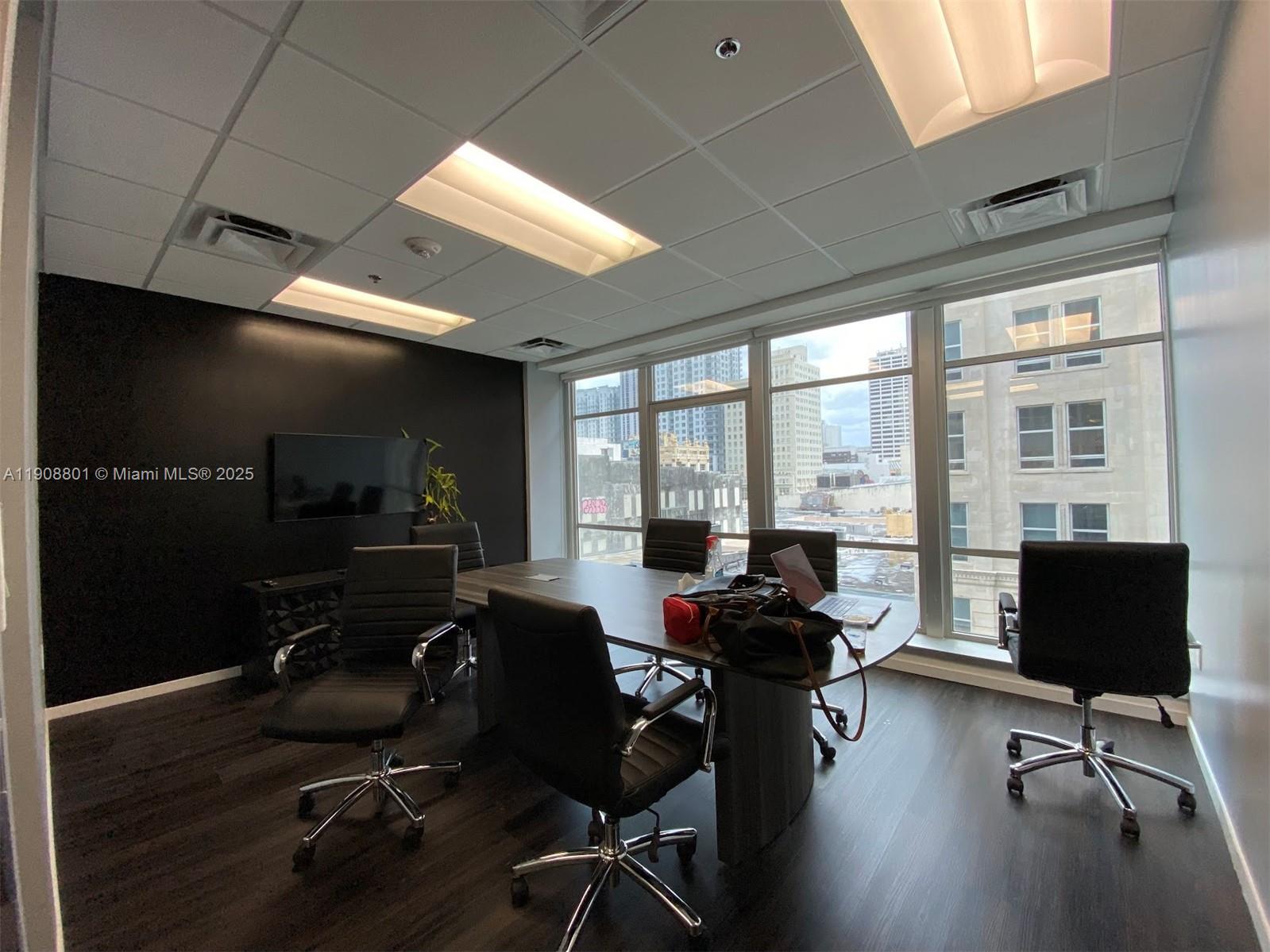 A modern conference room features a dark accent wall, a table with chairs, and city views — 14 NE 1st Ave # 600A, Miami FL 33132, MIAMI, FL