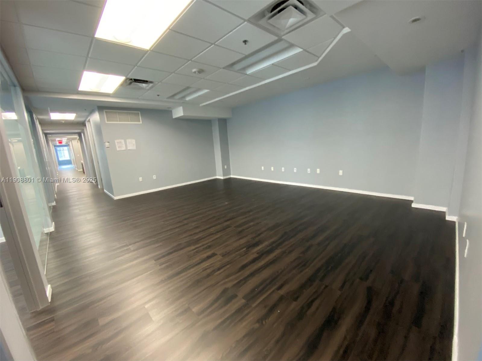 An empty office space features light blue walls, dark wood-look flooring, and a drop ceiling — 14 NE 1st Ave # 600A, Miami FL 33132, MIAMI, FL