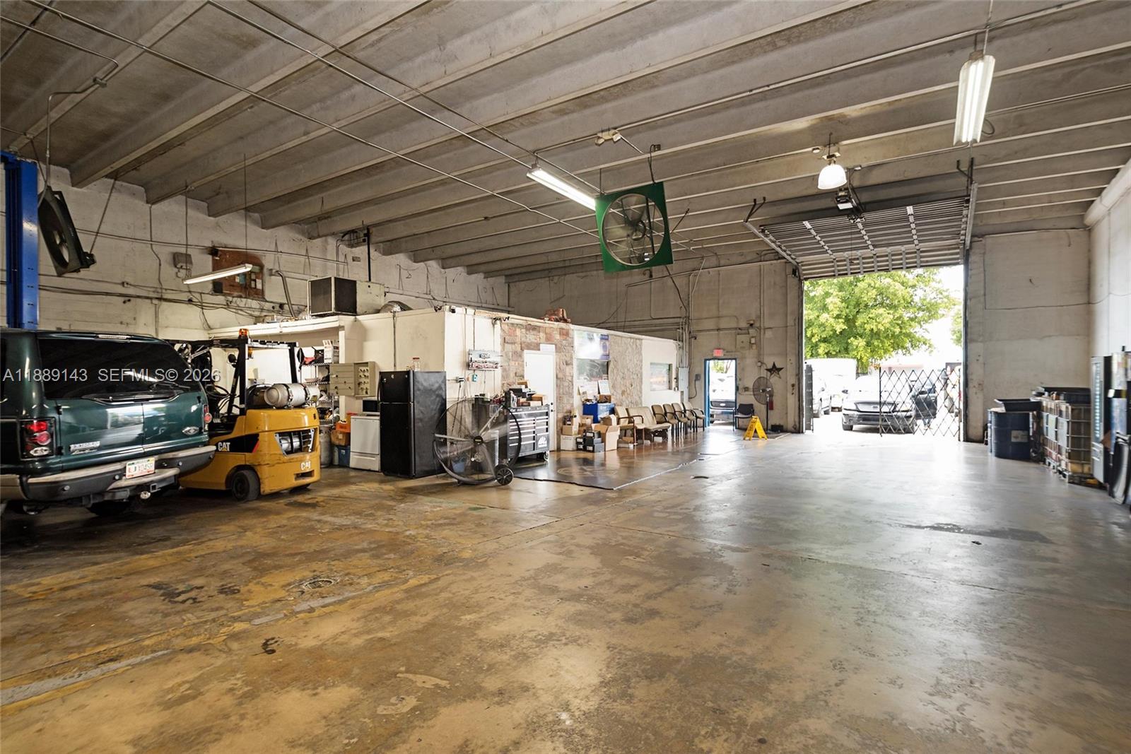 A spacious industrial garage features a concrete floor, high ceilings, and a large open bay — 8230 NW 56th St, Doral FL 33166, DORAL, FL