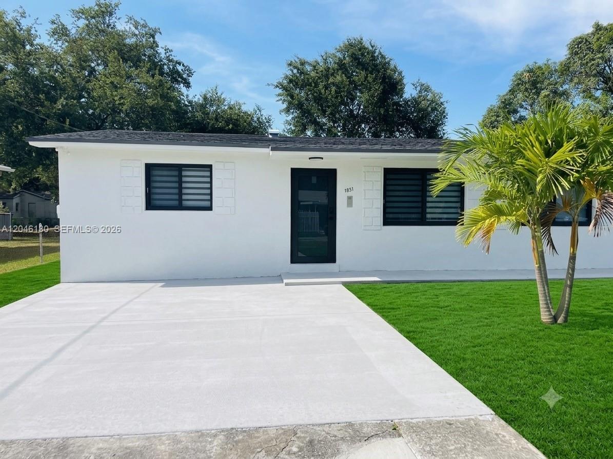 A single-story white house features a black front door, dark-framed windows, and a concrete driveway — 1855 NW 93rd Ter # 2, Miami FL 33147, MIAMI, FL
