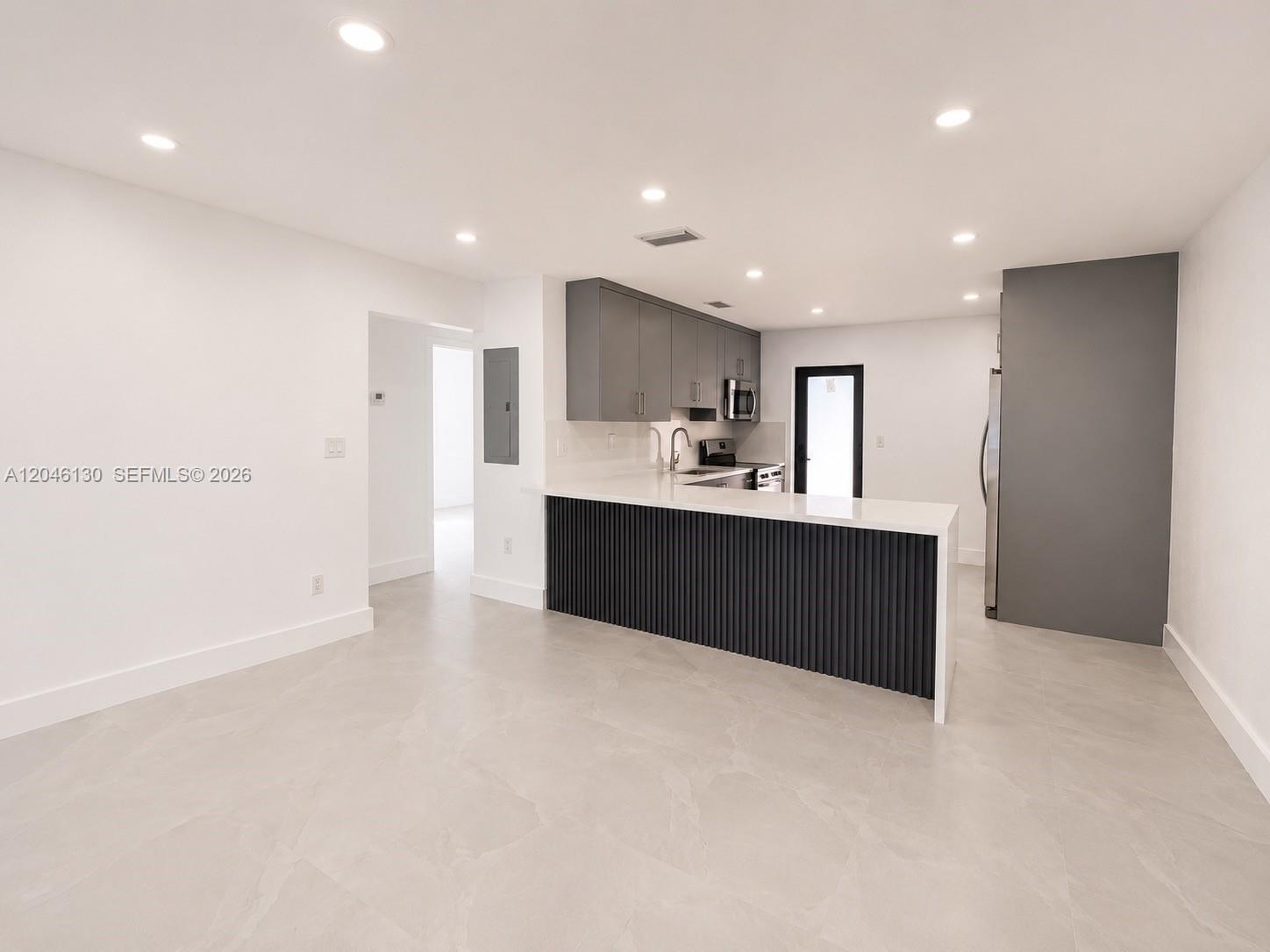 A modern kitchen features gray cabinets, a white countertop, and a slatted dark island base — 1855 NW 93rd Ter # 2, Miami FL 33147, MIAMI, FL