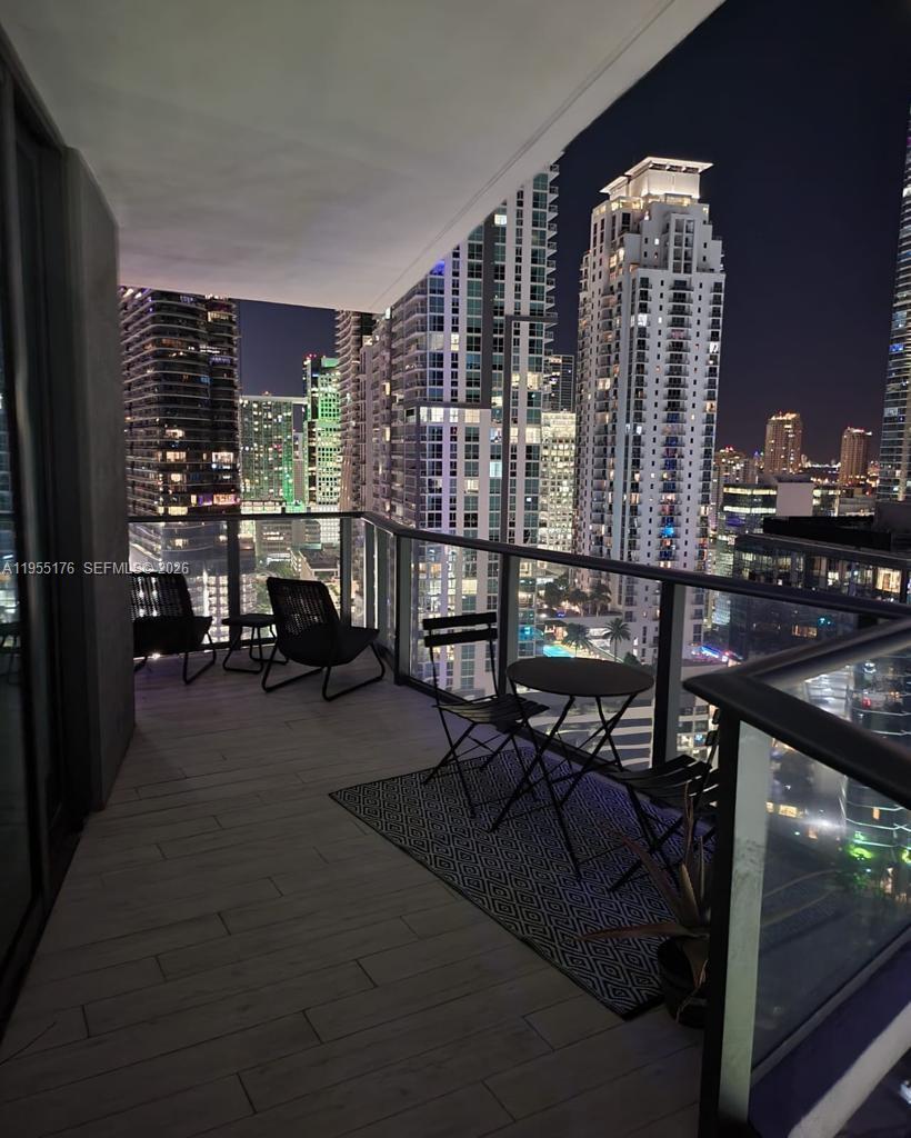 A balcony at night features outdoor furniture, a patterned rug, and city skyline views — 1300 S Miami Ave # 2501, Miami FL 33130, MIAMI, FL