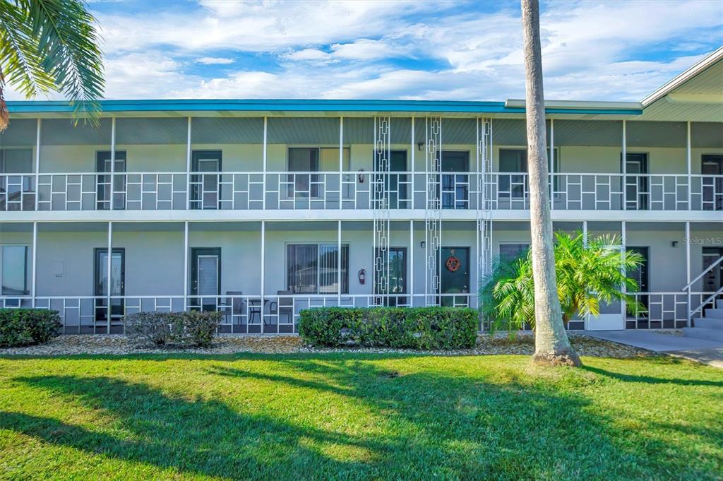A two-story apartment building features a white exterior with screened-in balconies and a lawn — 1600 W LAKE PARKER DRIVE UNIT D5, LAKELAND, FL