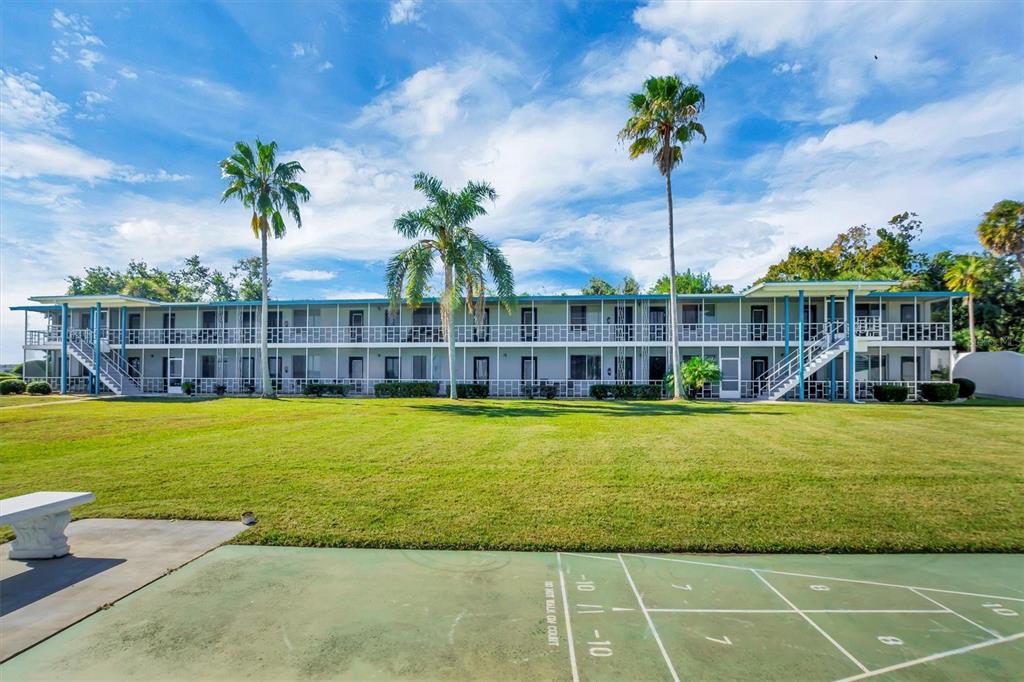 A two-story apartment building sits behind a green shuffleboard court under a blue sky — 1600 W LAKE PARKER DRIVE UNIT D5, LAKELAND, FL