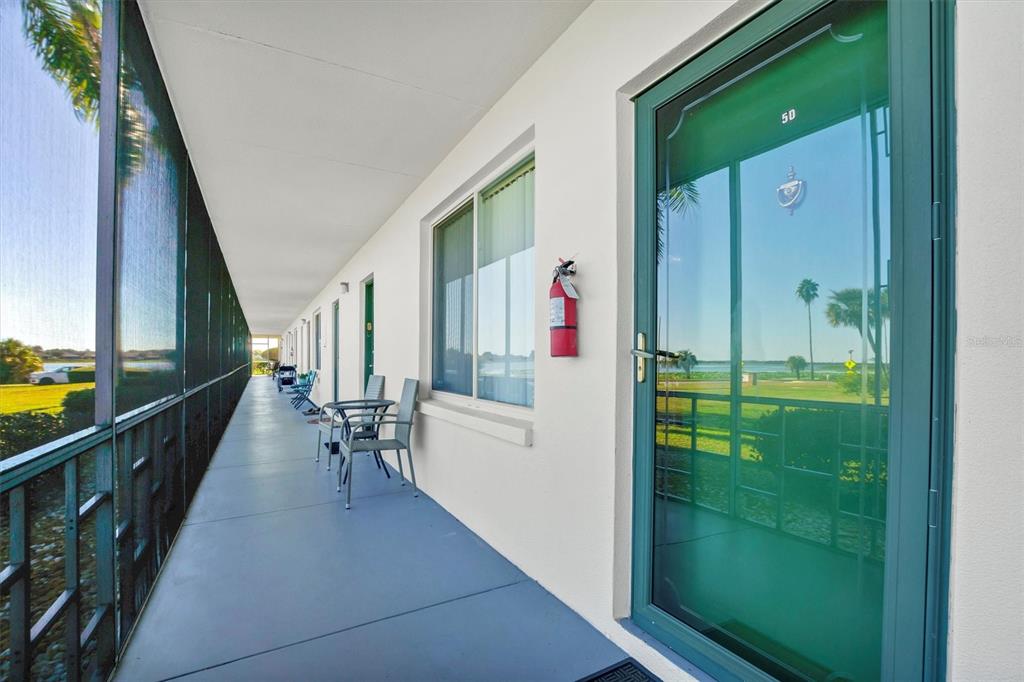 An outdoor walkway with a screen enclosure, a fire extinguisher, and a green door — 1600 W LAKE PARKER DRIVE UNIT D5, LAKELAND, FL
