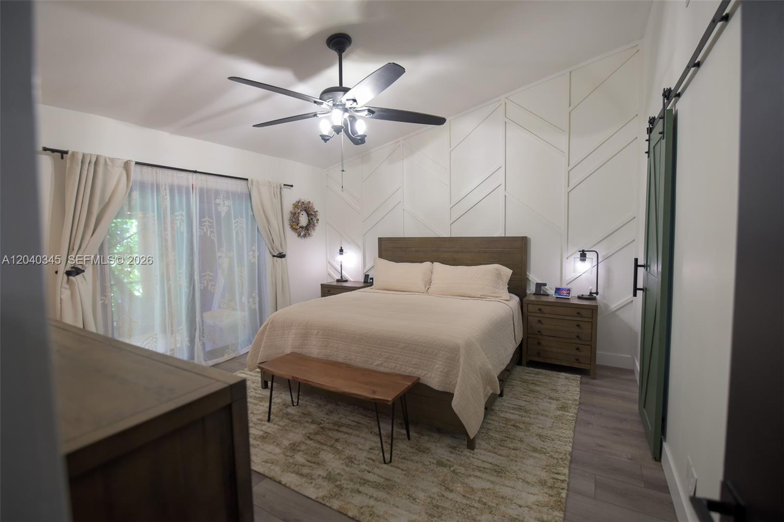 A bedroom features a bed with a geometric accent wall, ceiling fan, and sliding doors — 8356 NW 37th Pl # 9, Sunrise FL 33351, SUNRISE, FL