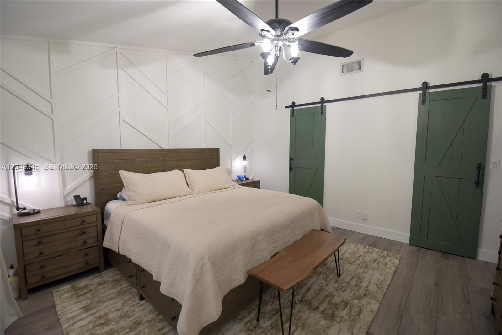 A bedroom features a wood bed, geometric wall molding, and two green sliding barn doors — 8356 NW 37th Pl # 9, Sunrise FL 33351, SUNRISE, FL