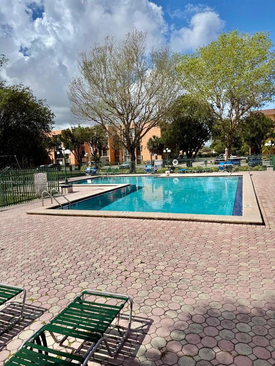 A swimming pool with a paved deck and lounge chairs sits before a residential building — 9400 WEST FLAGLER ST # 312, Miami FL 33174, MIAMI, FL