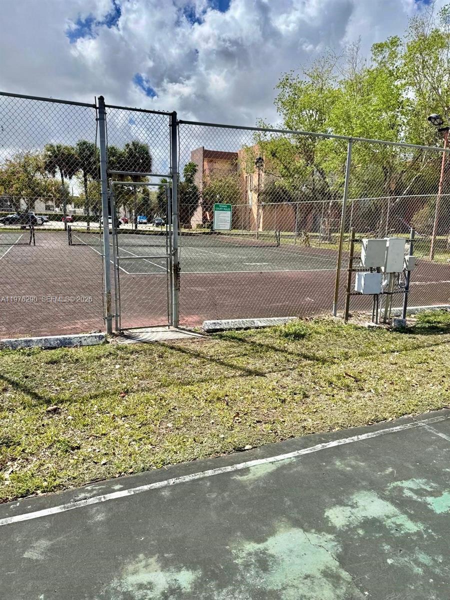 A chain-link fence surrounds a tennis court with a gate and electrical equipment — 9400 WEST FLAGLER ST # 312, Miami FL 33174, MIAMI, FL