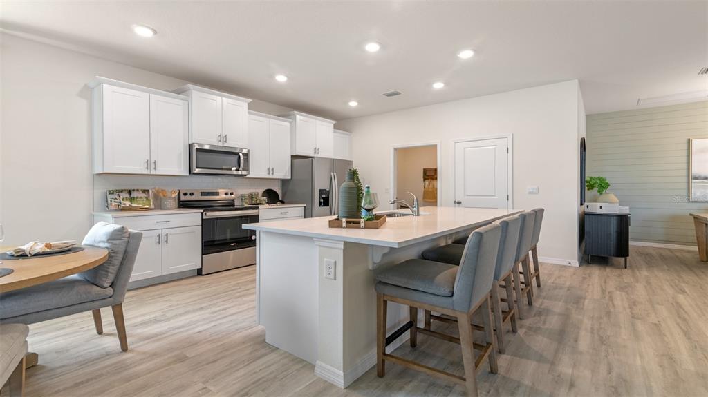 A modern kitchen features white cabinetry, stainless steel appliances, and a large central island — 3042 KINGSMAN TRAIL, ORMOND BEACH, FL